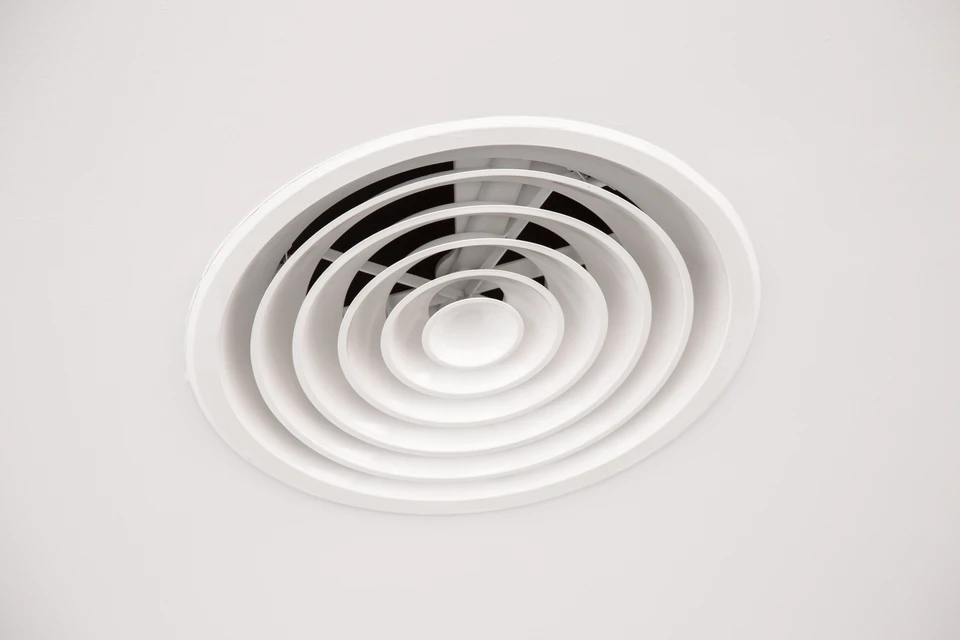 Intérieur résidentiel avec grille d'aération circulaire blanche montée au plafond