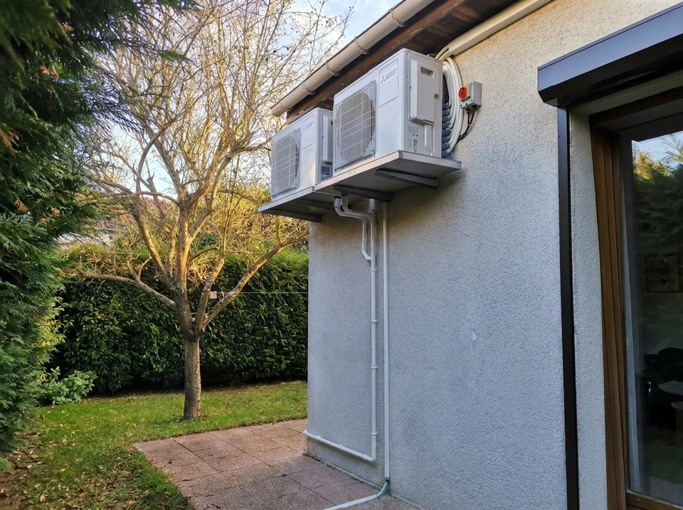 Un technicien en casque de sécurité blanc effectue la maintenance d'un système de climatisation encastré au plafond dans un intérieur résidentiel