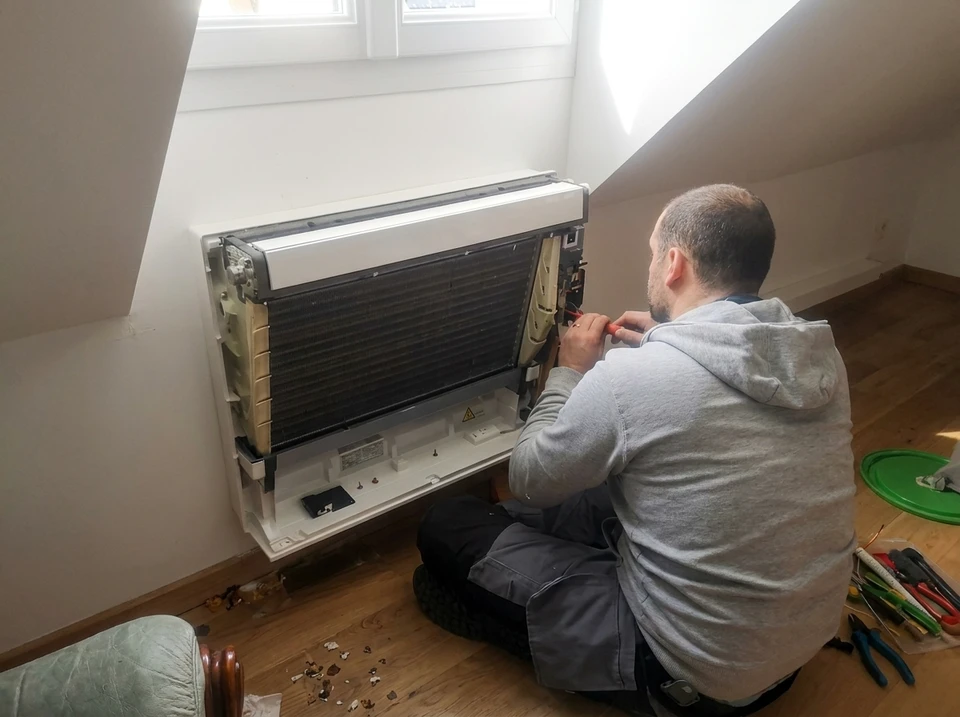 Technicien réparant une unité de climatisation murale intérieure
