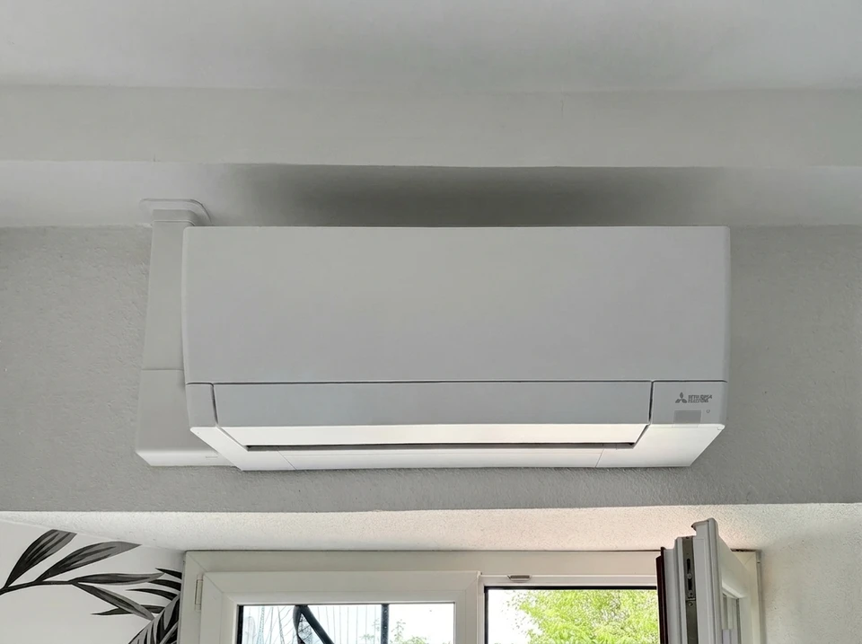 Extérieur résidentiel avec unité de climatisation/pompe à chaleur installée contre façade d'immeuble