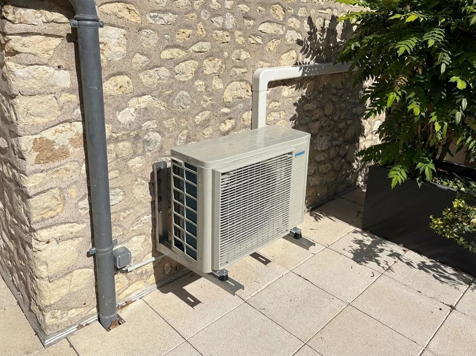 Plombier effectuant la maintenance d'un chauffe-eau électrique domestique, tenant un tournevis dans sa main