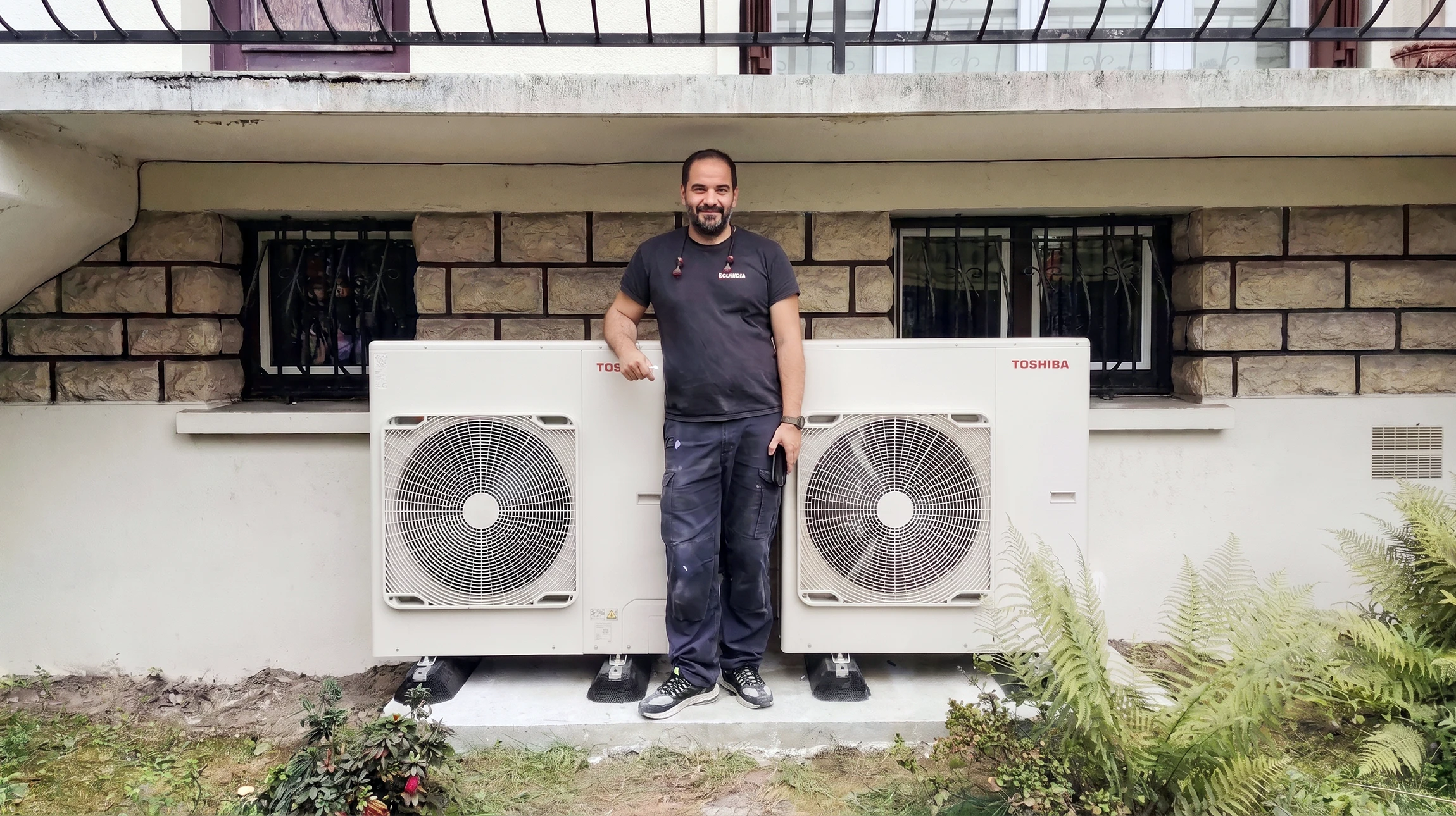 Extérieur résidentiel moderne avec pompe à chaleur air-eau installée sur gravier concassé gris, bordée de pelouse verte entretenue